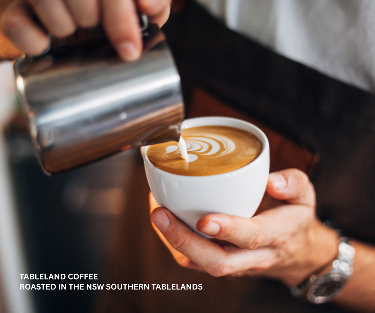 Barista pouring steamed milk into a cup of coffee to create latte art.